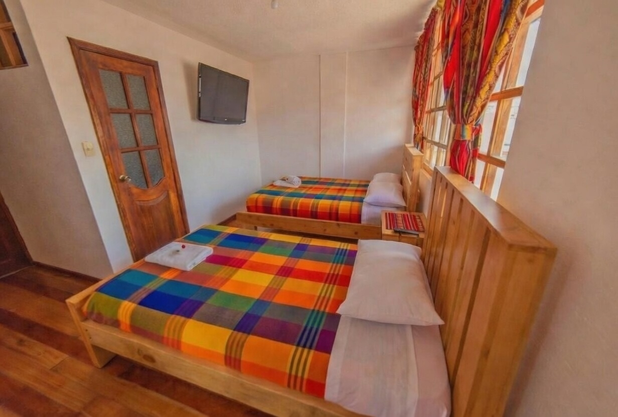 Habitación triple espaciosa con escritorio y sofá en Otavalo